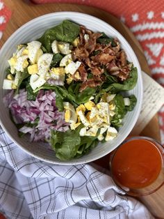 a white bowl filled with salad next to a glass of orange juice