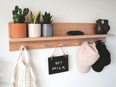 a wooden shelf with two potted plants on top of it and some hanging items next to it