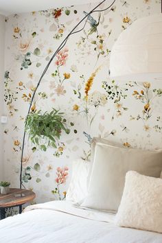 a bedroom with floral wallpaper and white bedding