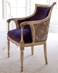 a purple chair sitting on top of a carpeted floor next to a vase with flowers