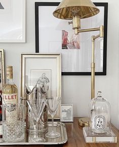 a table topped with bottles and glasses on top of a wooden table next to framed pictures