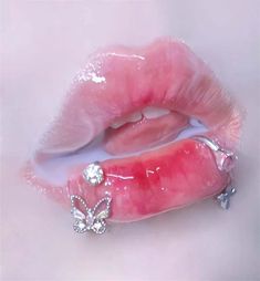 a close up of a pink lip with a butterfly brooch on it's end