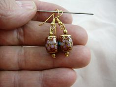 a pair of earrings is being held in someone's hand