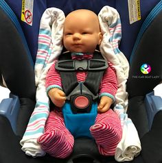 a baby doll sitting in a car seat with its head on the back of it