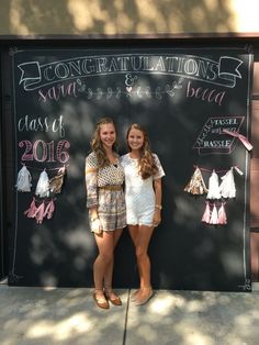 two girls standing in front of a chalkboard sign