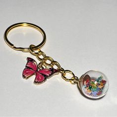 a keychain with a glass ball and butterfly charm on the front, sitting on a white surface