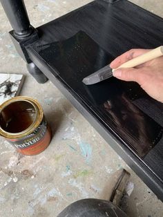 a person using a paint brush on top of a black table next to a can