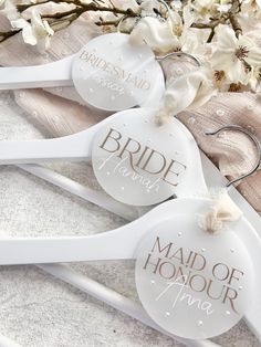 three bride hangers with the names of their wedding day on them and flowers in the background