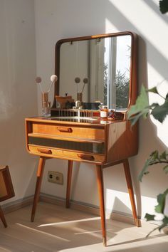 an old vanity with mirror and stool in the corner next to a potted plant