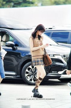 a woman is walking down the street looking at her cell phone