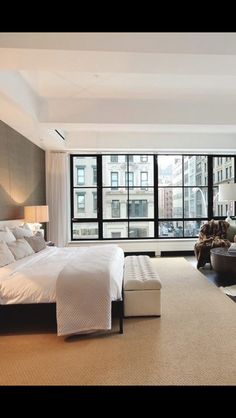 a bedroom with a large bed and lots of windows