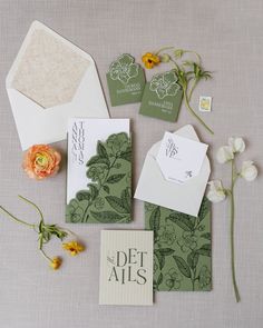 the wedding stationery is laid out with flowers and envelopes