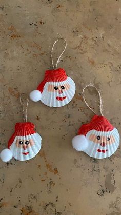 three christmas ornaments are hanging from strings on the ground, one is wearing a santa claus hat