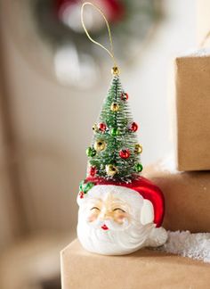 a santa clause ornament sitting on top of a stack of boxes next to a christmas tree