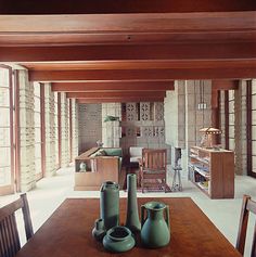 there are three vases sitting on the table in this dining room, and one is empty