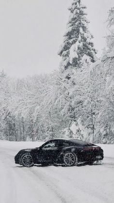 a black car driving down a snow covered road