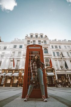 a woman standing in front of a red phone booth