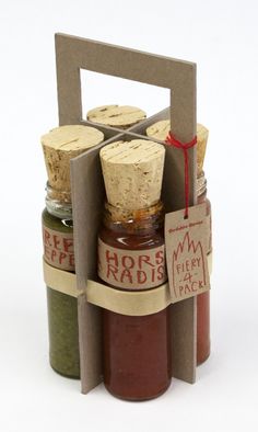 three jars with different types of condiments in them, sitting inside a cardboard holder