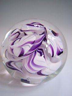 a purple and white swirled glass ball on a table