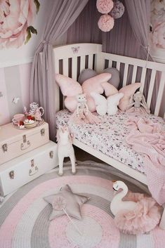 a pink and white bedroom with flowers on the walls, bedding and furniture in it