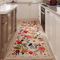 a kitchen with white cabinets and an area rug that has colorful flowers on the floor