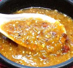 a spoon full of soup on top of a red table cloth with a wooden spoon in it