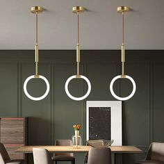 three circular lights hang from the ceiling above a dining room table with chairs and a vase