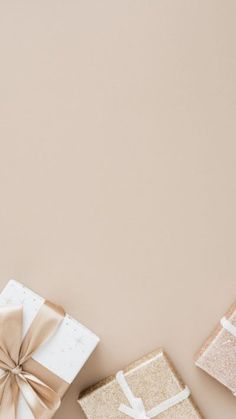 three gift boxes with bows on them sitting next to each other in front of a beige background