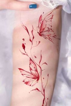 a woman's arm with red flowers and butterflies painted on the back of it