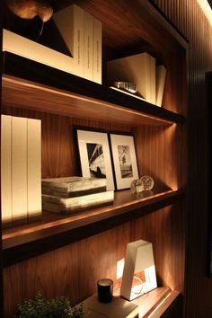 a shelf with books and pictures on it in a room that has wood paneling