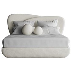 a white bed with pillows and two balls on the headboard in front of it