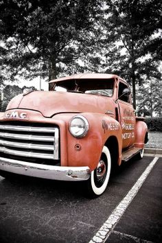 an old red truck parked in a parking lot