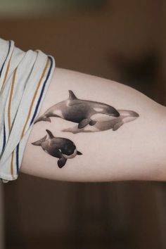 a woman's arm with two orca whales on it