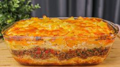 a casserole dish with meat and vegetables in it sitting on a wooden table