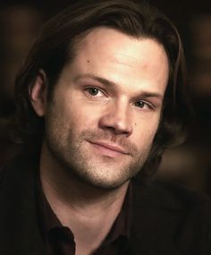 a close up of a person wearing a black shirt and looking at the camera with a serious look on his face