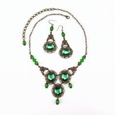 Marquesa Questa jeweled Renaissance necklace in antique bronze metals with emerald green gems Some jewelry was simply made to turn heads. Attract the wandering eye of a nobleman or even a prince with an enticing accessory. Slip on this Marquesa Questa jeweled Renaissance necklace and revel in the stares and praise.This jaw-dropping necklace features three brilliant oval emerald green gems, each mounted in antique bronze. Faceted emerald green crystals capped in the same bronze filigree hang from Antique Gold Metal Jewelry With Antique Finish, Green Jeweled Emerald Necklace, Green Emerald Jeweled Necklace, Gothic Metal Jewelry With Antique Finish, Antique Jeweled Metal Jewelry, Ornate Antique Gold Metal Jewelry, Jeweled Antique Gold Brass Jewelry, Victorian Style Metal Jewelry With Jewels, Antique Green Jeweled Necklaces