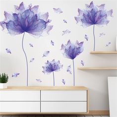 purple flowers with butterflies flying around them on a white wall in a living room area