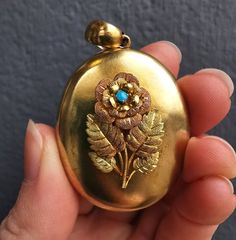 A beautiful Victorian era locket, made in 15ct yellow gold, featuring an applied flower to the front with wonderful detail; the leaves and petals are engraved, and there is a small turquoise set to the middle of the flower. The locket opens to reveal space for two photographs inside. With a pendant loop, ready to be hung on a neckchain.Circa 1890.Unmarked, tested as 15ct gold.The locket measures approximately 50mm (including halter) x 31.8mm.The flower and stem to the front measures approximatel Victorian Turquoise Jewelry For Wedding, Turquoise Locket For Wedding Jewelry, Turquoise Wedding Locket Jewelry, Turquoise Locket Jewelry For Wedding, Antique Gold Flower Jewelry, Heirloom Flower-shaped Engraved Jewelry, Heirloom Flower Engraved Jewelry, Victorian Hallmarked Turquoise Jewelry, Victorian Turquoise Hallmarked Jewelry