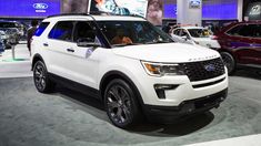 a white suv is on display at an auto show with other cars in the background