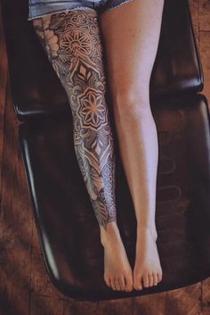 a woman's legs with tattoos sitting on top of a chair