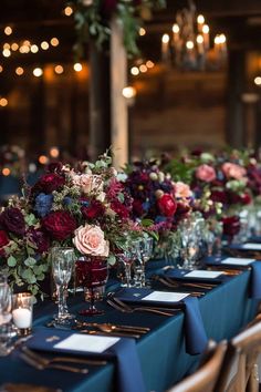 the table is set with wine glasses, candles and floral centerpieces on it