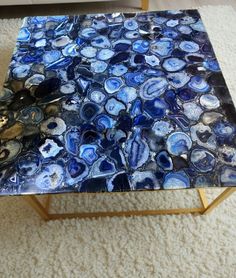 a blue and white marble coffee table sitting on top of a carpeted floor next to a couch