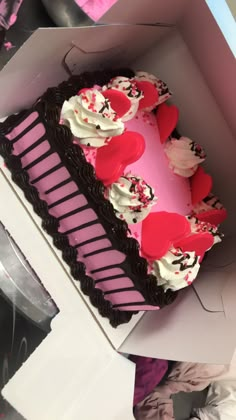 a heart shaped cake in a box with pink frosting and hearts on the top