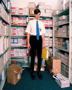 a man standing in front of shelves with boxes and file folders on the floor