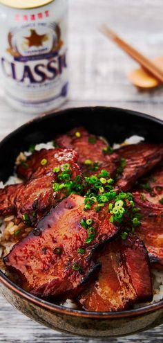 a bowl filled with meat and rice on top of a table