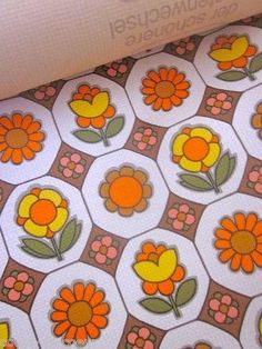 an orange and yellow flower pattern is on the ground next to a white wallpaper