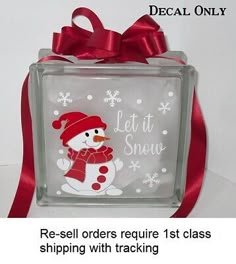 a glass block with a snowman on it and a red ribbon around the bottom