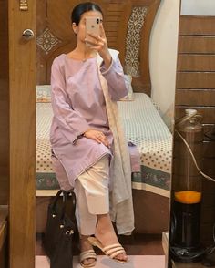 a woman taking a selfie in front of a mirror while sitting on a bed