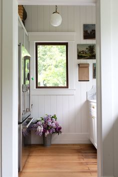 an open door leading to a kitchen with white walls and wood flooring on the side