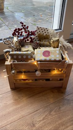 a wooden crate filled with lots of wrapped presents on top of a hard wood floor